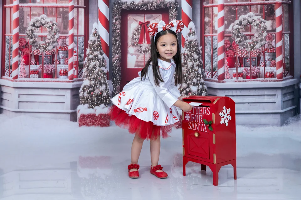 Retrato infantil junto a un buzón rojo de Navidad.
