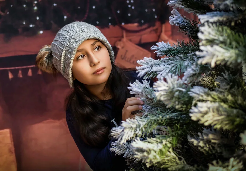 Retrato junto a las ramas de un árbol navideño nevado.
