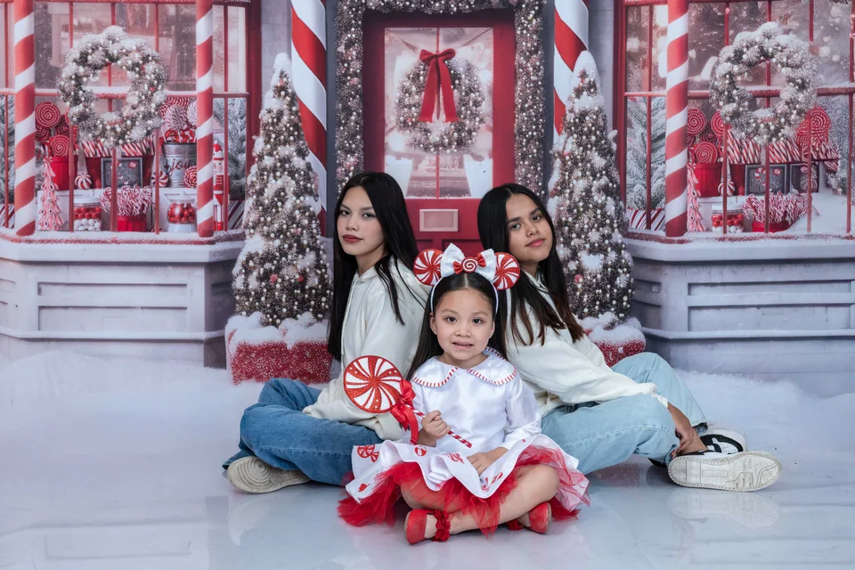Tres participantes comparten un retrato en un escenario navideño.